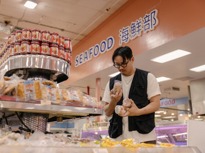An Asian man looks at items in a grocery store.