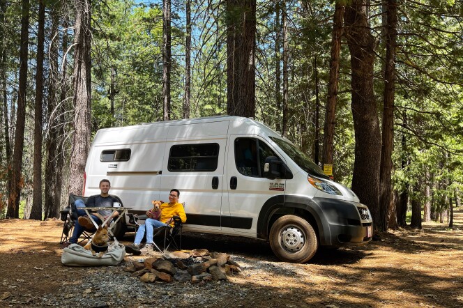 Patrick and Arthur at a campsite with their van and two dogs.