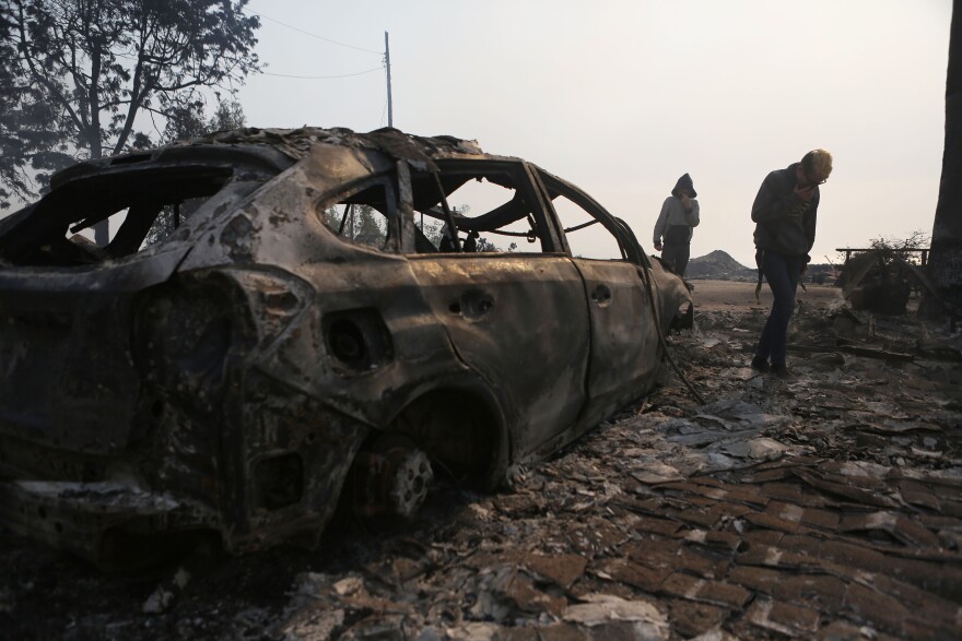 Residents walk amidst the remains of an apartment complex destroyed by the Thomas Fire in a residential neighborhood on Dec. 5, 2017 in Ventura.