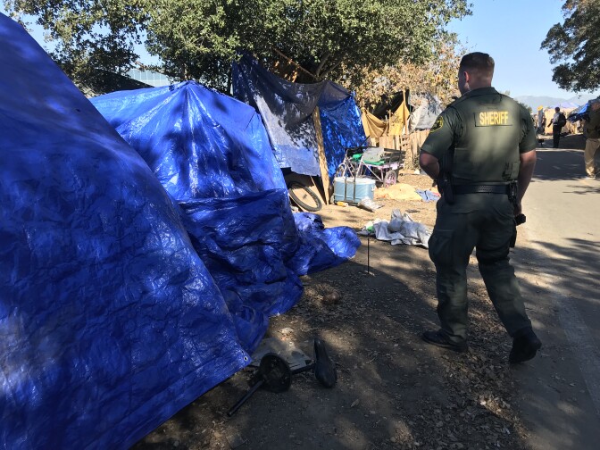 An Orange County Sheriff's deputy patrols the homeless encampment along the Santa Ana River near Angel Stadium on Jan. 22, 2018. A federal judge ordered the county on Feb. 7 not to enforce anti-trespassing laws in the area until the court can decide on the merits of a request for an injunction from lawyers for the homeless.
