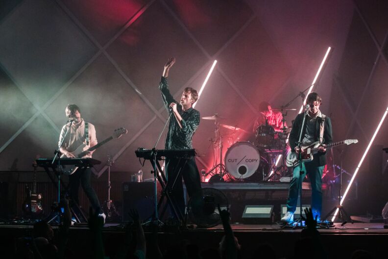 Four performer band on stage with lights and fog.