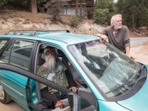 Wayne Trott and David Atwood wait by their car after being evacuated from Idyllwild, Calif. due to the Mountain Fire.