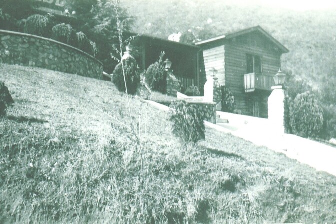 A brick and wood structure is seen in black and white. The Verdugo Lodge is at the top of a hill. 