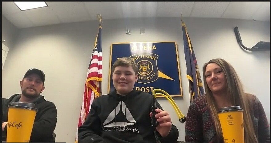 Owen Burns, center, holds up the slingshot he used to fend off a boy who was attacking his sister earlier this month.