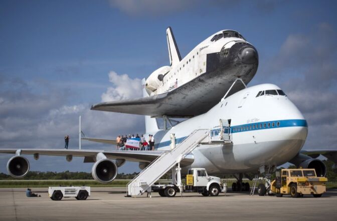 In this handout provided by NASA, Workers pose for a photograph on the wing of NASA's Shuttle Carrier Aircraft, or SCA, with the space shuttle Endeavour mated on top, at the NASA Kennedy Space Center, Shuttle Landing Facility on Sept. 18, 2012 in Cape Canaveral, Florida.