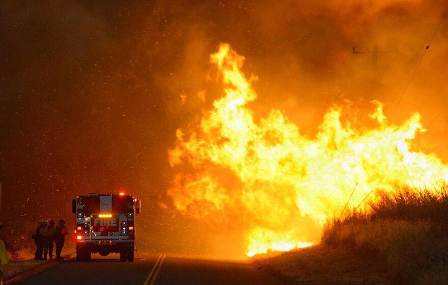 Firefighters take shelter behind the engine as flames advance on them along near El Capitan State Beach on Thursday, June 16, 2016.