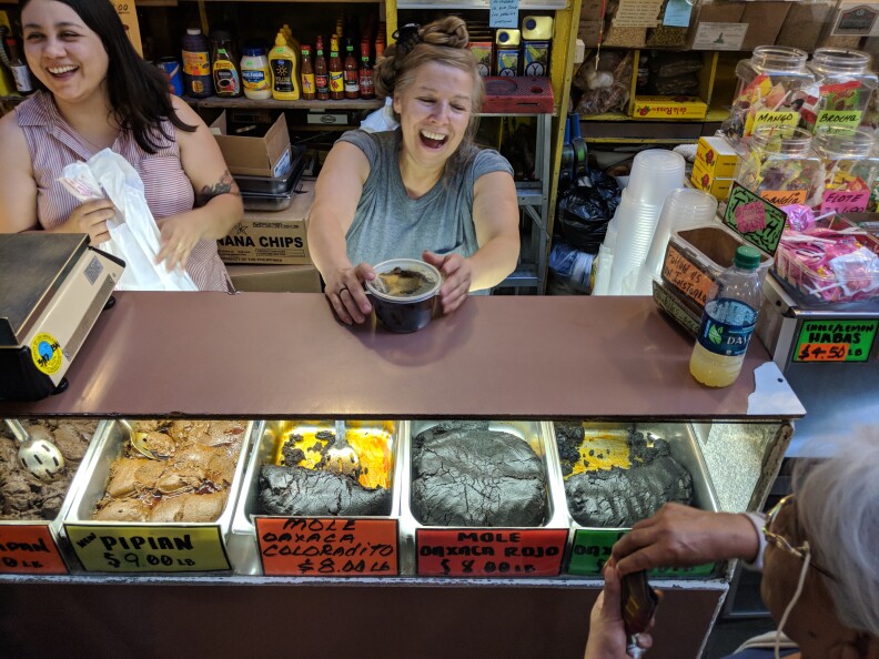 Claudia Armendariz (L) and her aunt Rocio Lopez serve molé paste to a customer at their stall Chiles Secos at Grand Central Market.