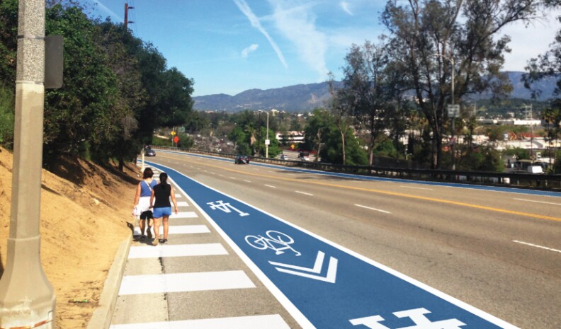 A photo illustration shows architect Daveed Kapoor's dream: Two people walk safely along a wide pedestrian pathway marked by white stripes. Nearby, there's a bike path painted -- what else? -- Dodger Blue and accented at intervals by the team logo and bike symbols and arrows, all pointing the way to the stadium.