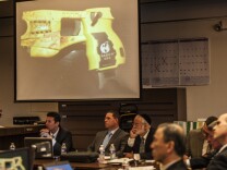 Orange County District Attorney Tony Rackauckas shows the jury an image of taser gun like the one that Fullerton police officer Jay Cicinelli used to strike Kelly Thomas during an encounter at the Fullerton Transportation Center on July 5, 2011 as Cicinelli sits below the image under the handle of the gun on Monday, Dec. 2, 2013 in Santa Ana, Calif.  Rackauckas  told jurors that former Fullerton officers Cicinelli and Manuel Ramos were responsible for the death of 37-year-old Kelly Thomas in July 2011. Thomas, whose family says was schizophrenic, died five days after the violent confrontation with six officers who responded to a call about a man jiggling car door handles in a transit center parking lot. Ramos is charged with second-degree murder and involuntary manslaughter. Cicinelli is charged with to involuntary manslaughter and use of excessive force.  Barnett portrayed Thomas as an unpredictably violent person in his opening statements.