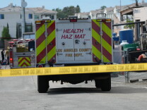 Emergency vehicles are parked on a street behind yellow tape.