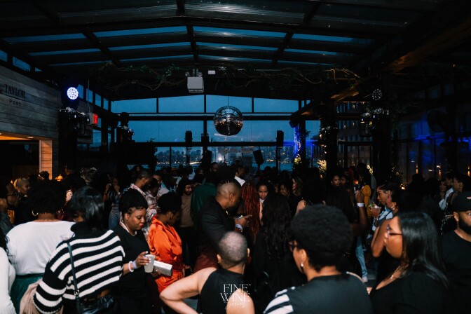 A bar full of mostly Black customers, all enjoying wine and wine cocktails during a Fine Wine Series event. 