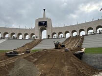 Dirt and a tractor inside an open-air L.A. Colisuem 