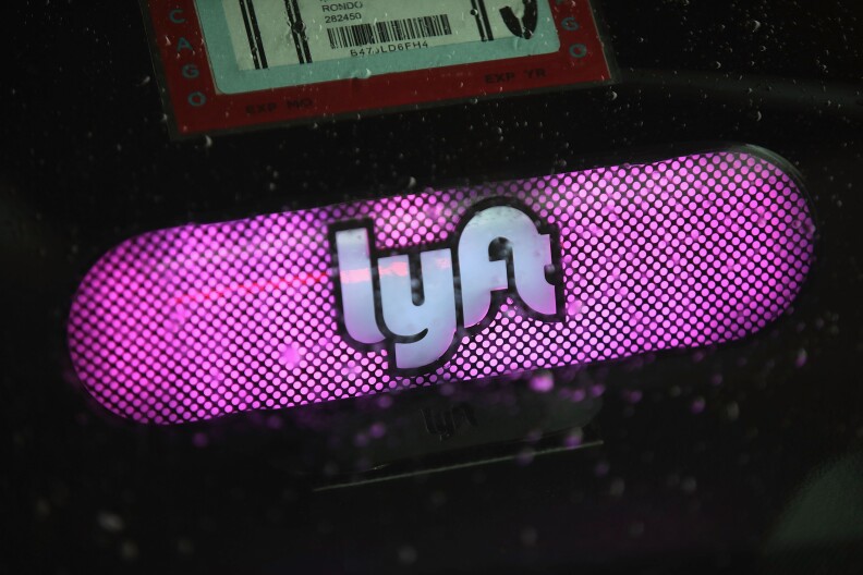 A pill-shaped sign glows pink, made up of countless little LED lights. The company name "lyft" appears in white lettering, outlined in bold black lines, in the center of the sign.