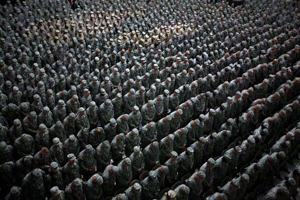 1,215 American soldiers, airmen, marines (patch of lighter uniforms in top left corner) and seamen (patch of lighter uniforms in top center) pray before the pledge of enlistment on July 4, 2008, at a massive re-enlistment ceremony in Al Faw palace in Baghdad, Iraq on July 4, 2008. (Photo by Ashley Gilbertson / VII Network)