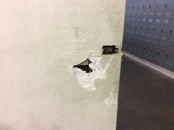 An inspector's photo shows holes in the wall of a boys' bathroom at Inglewood High School.
