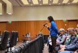 Man stands at microphone at U.C. Regents meeting during public comments