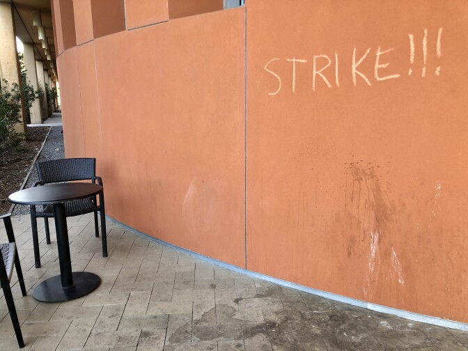 The word Strike!!! is written in chalk on a rust colored wall.