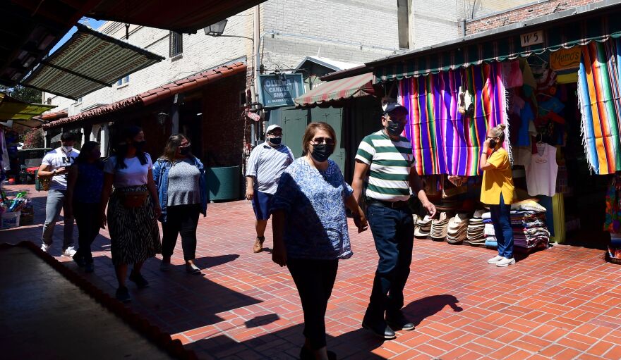 Face masks remain worn as people walk along Olvera Street in Los Angeles on June 14, 2021, one day before the state full reopening of its economy since the first statewide shutdown in March 2020 due to the coronavirus pandemic. - California is removing nearly all pandemic restrictions on June 15, with no mandatory capacity restrictions or social distancing requirements for those who have been vaccinated. (Photo by Frederic J. BROWN / AFP) (Photo by FREDERIC J. BROWN/AFP via Getty Images)