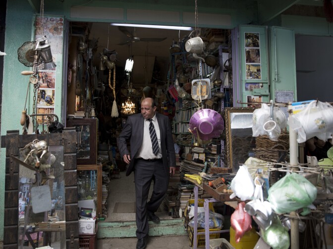 Ayman Hassouna, who taught archaeology in Gaza, walks out of an antiques shop in the middle of the main market in Gaza's Old City, in 2019.