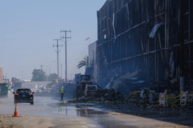 Crews clean up debris from a burned building.