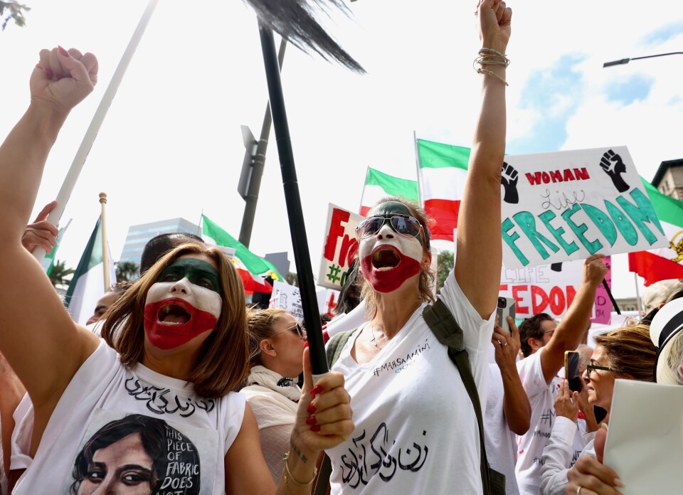 Women with their faces painted green, white and red wear shirts with Masha Amini's face.