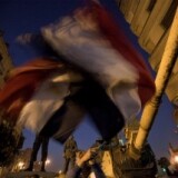 Anti-government protesters wave Egyptian flags in front of an army tank as demonstrators at Cairo's Tahrir Square react after President Hosni Mubarak stepped down on February 11, 2011.