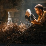 Two people in a cave, examining a dinosaur's egg