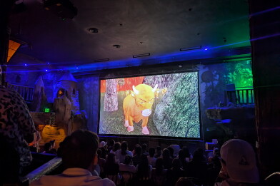 A group of people in a theater watching a film about an animated cow.