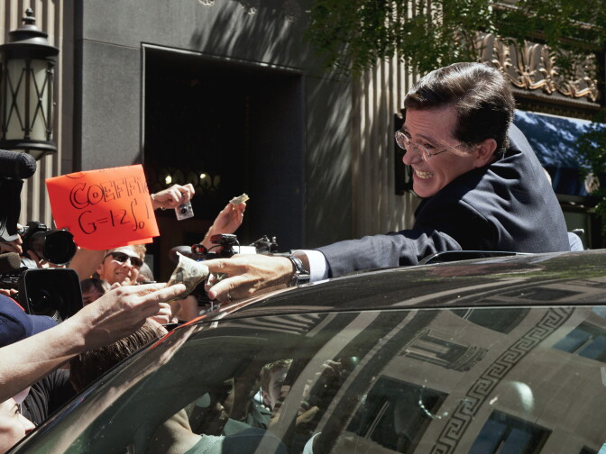 Comedian Stephen Colbert grabs cash money from a supporter as he climbs into a vehicle to depart the Federal Election Commission in Washington, Thursday, June 30, 2011, after the FEC granted his request to form a Political Action Committee. (AP Photo/Cliff Owen)