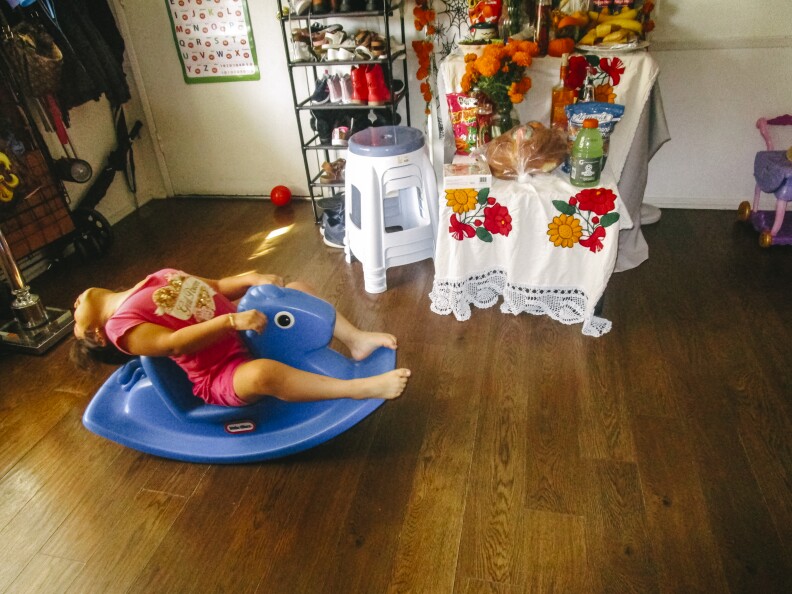 This is an image of a young girl rocking back and forth on a blue plastic rocking horse.
