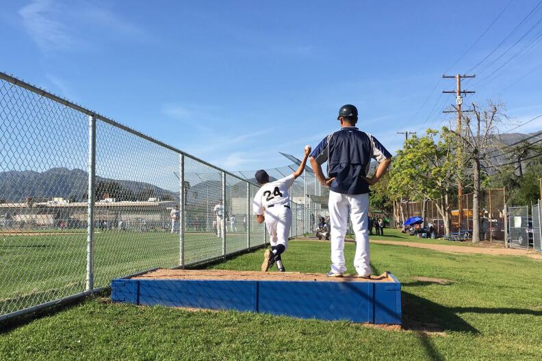 John Muir High School Pitcher Bryan Barrios warms up with coach Robert Galvan. 