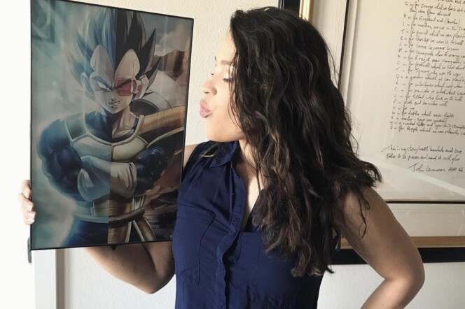 A Latina woman with dark wavy hair puckers her lips at a picture of Vegeta, a character in the Dragon Ball franchise. 