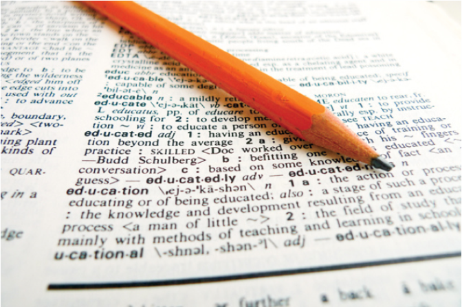 A pencil rests on top of a dictionary showing the definition for the word "education"