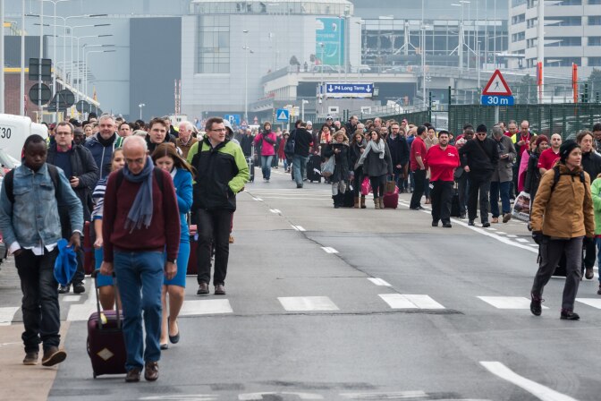 People walk away from Brussels airport after explosions rocked the facility in Brussels, Belgium Tuesday March 22, 2016.   Explosions rocked the Brussels airport and the subway system Tuesday, just days after the main suspect in the November Paris attacks was arrested in the city, police said. (AP Photo/Geert Vanden Wijngaert)