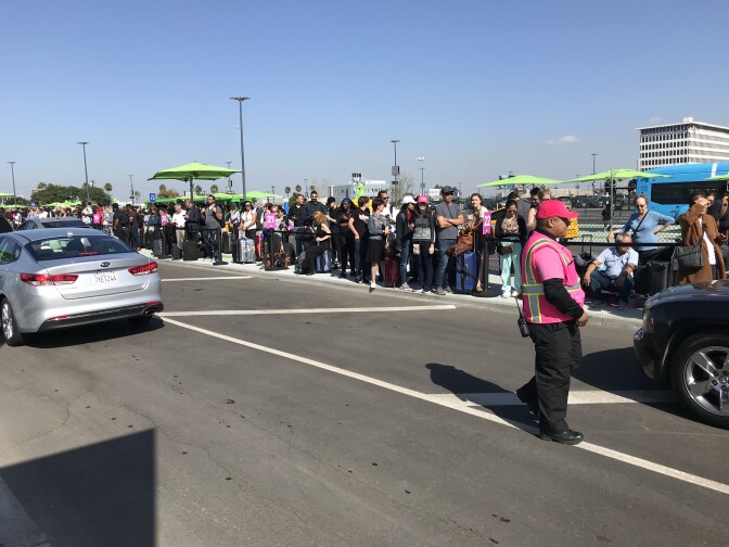 Passengers cluster together, waiting for Lyft rides at LAX's new rideshare pickup zone, Oct. 29, 2019. 