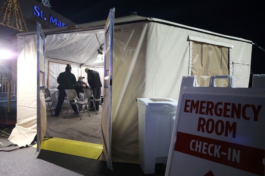 APPLE VALLEY, CALIFORNIA - DECEMBER 18:  Clinicians evaluate a patient in a triage tent set up outside Providence St. Mary Medical Center amid a surge in COVID-19 patients in Southern California on December 18, 2020 in Apple Valley, California. The 213 bed capacity hospital in San Bernardino County currently has 60 ICU-level patients with only 20 official ICU beds. The hospital is currently treating 131 COVID 19-positive patients while 20 more patients are suspected to have the virus. Southern California currently has zero percent of its ICU (Intensive Care Unit) bed capacity remaining amid the spike in coronavirus cases and hospitalizations. (Photo by Mario Tama/Getty Images)