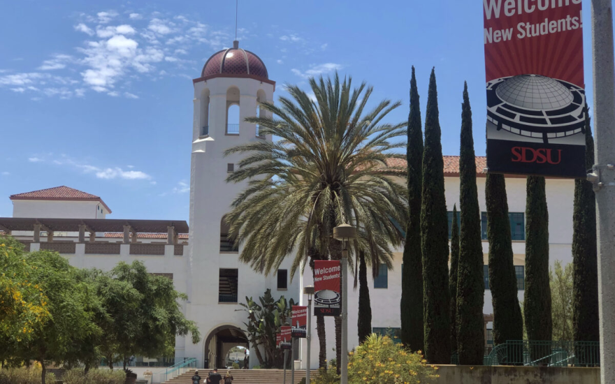 A white building with a bell tower and a dome alongside other buildings on a university campus 