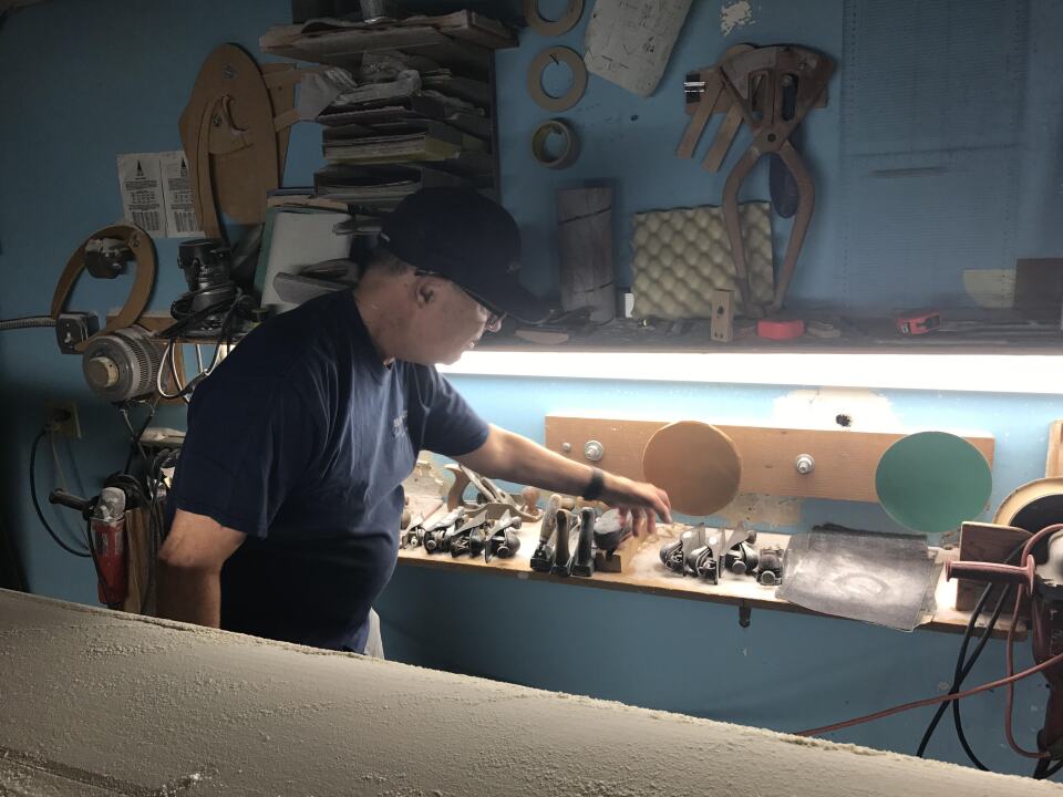 Rich Harbour reaches for the tools that help him smooth and shape the surfboard decks to his specficiations.