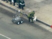 A bomb squad robot and a member of the squad outside an East L.A. bank on Wednesday, Sept. 5, 2012.
