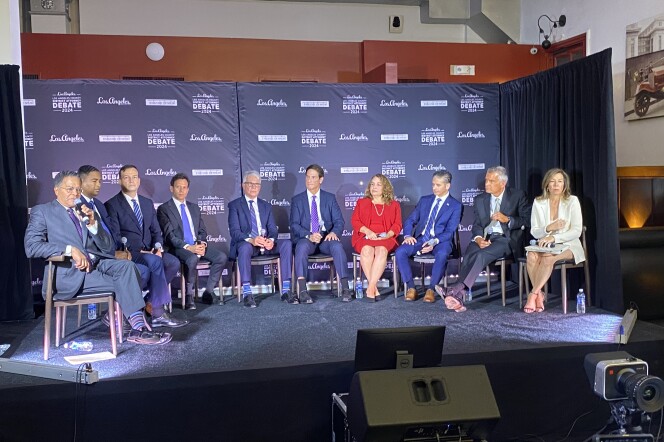 Ten people sit in chairs on a stage.