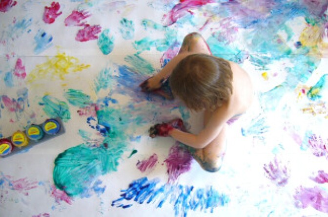 A young child plays with finger paints.