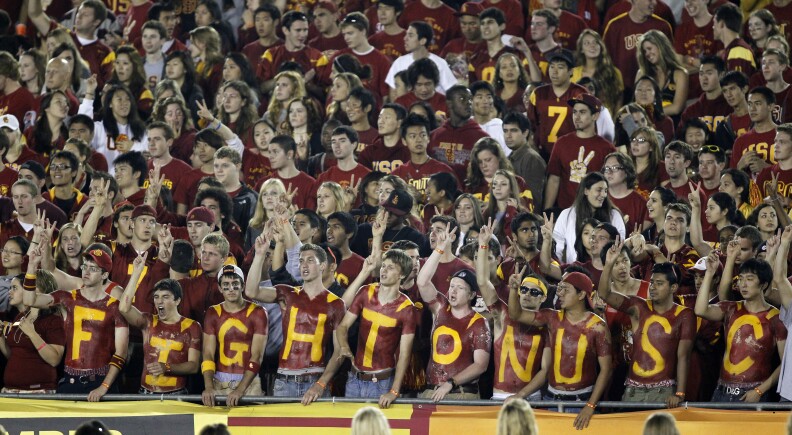 Fans cheer with their chests painted in the student section of the Los Angeles Memorial Coliseum during an NCAA college football game between Southern California and Virginia in Los Angeles on Saturday, Sept. 11, 2010. (AP Photo/Danny Moloshok)