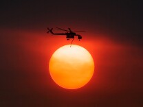 Smoke from the Mountain Fire obscures the sun as a fire fighting helicopter heads to fight the Mountain Fire after picking up water from Lake Hemet July 18, 2013 near Idyllwild, California. 