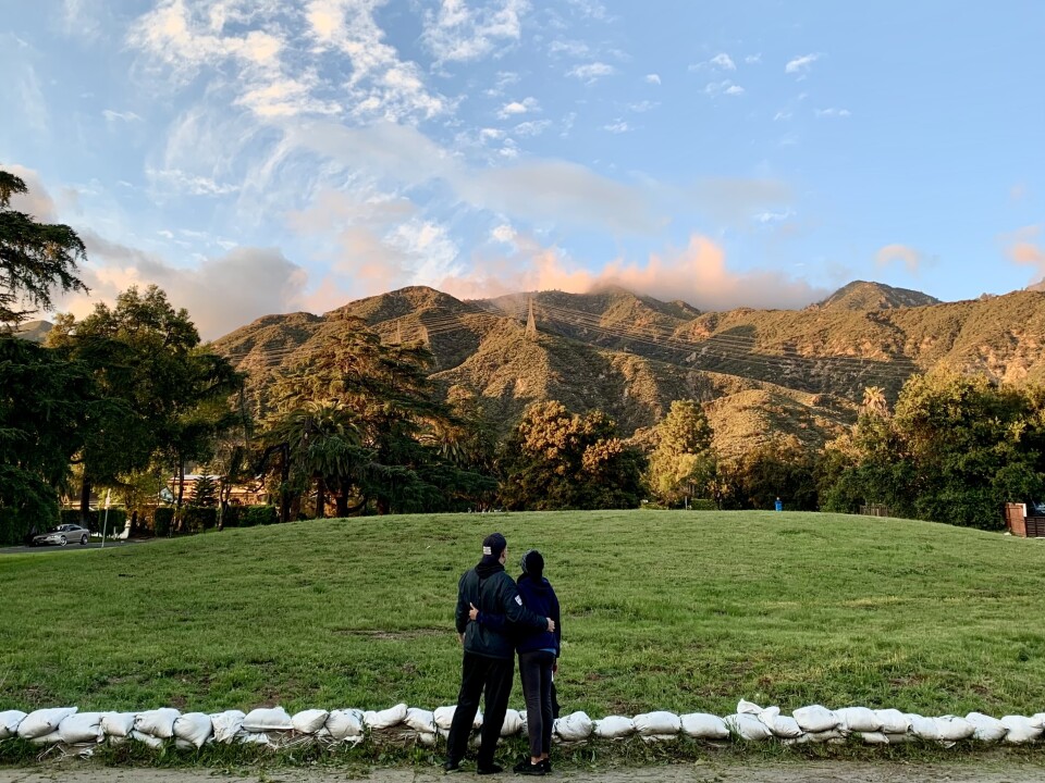 A couple, with their backs turned to the camera, look at the foothills surrounding Altadena. 