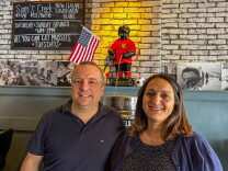 Thomas Crijns and his wife, Carol, at Brussels Bistro in San Clemente. The Manneken-Pis statue behind them, dressed in a Belgian national team jersey, is one of the restaurant's many nods to the World Cup.