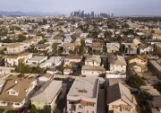 Aerial view of housing in Los Angeles with a view to the city's downtown skyline in the distance.