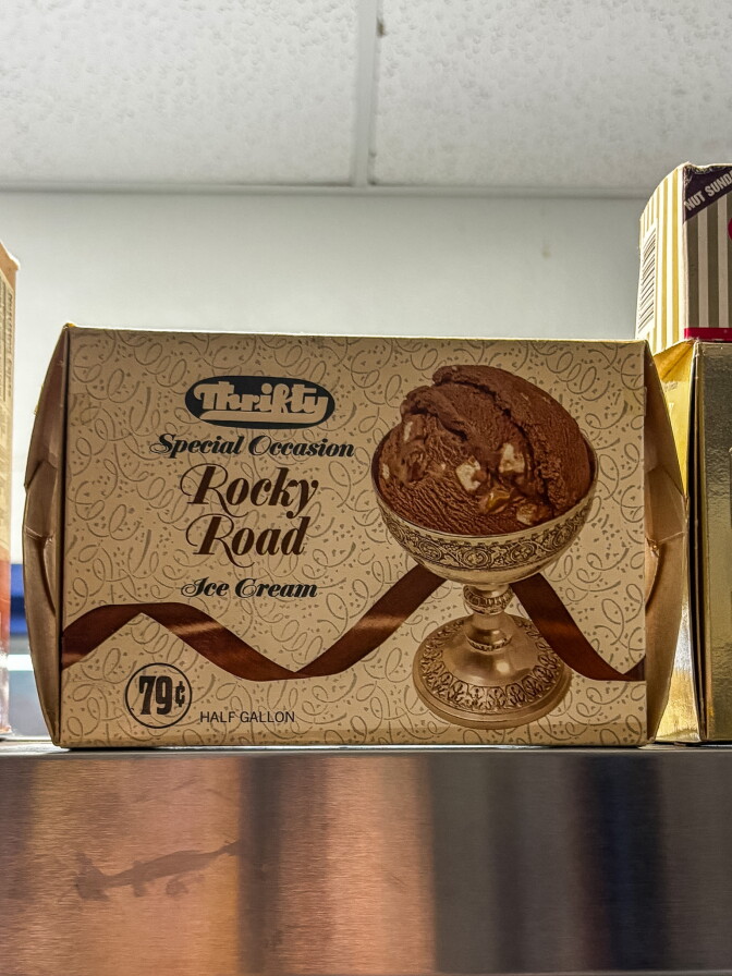 A vintage cardboard Thrifty ice cream box labeled "Special Occasion Rocky Road Ice Cream," priced at 79 cents for a half gallon, displayed on a shelf next to other vintage packaging.
