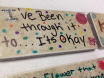 A young girl writes, "I've been through it too...it's okay," on a brick as away to deal with the experiences of forced prostitution at an empowerment conference for girls. 