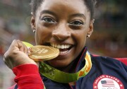 United States' Simone Biles bites her gold medal for the artistic gymnastics women's individual all-around final at the 2016 Summer Olympics in Rio de Janeiro, Brazil, Thursday, Aug. 11, 2016