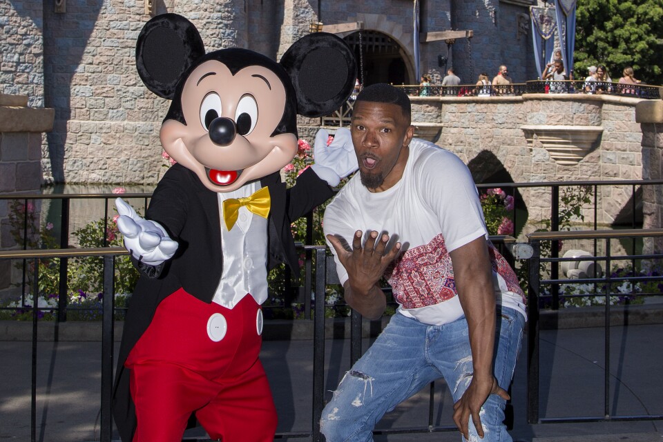 Actor Jamie Foxx meets Mickey Mouse in front of the Sleeping Beauty Castle at Disneyland in Anaheim, California on July 3, 2017.